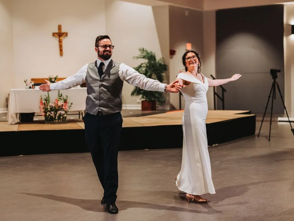 A father and bride open their arms to the room during their dance