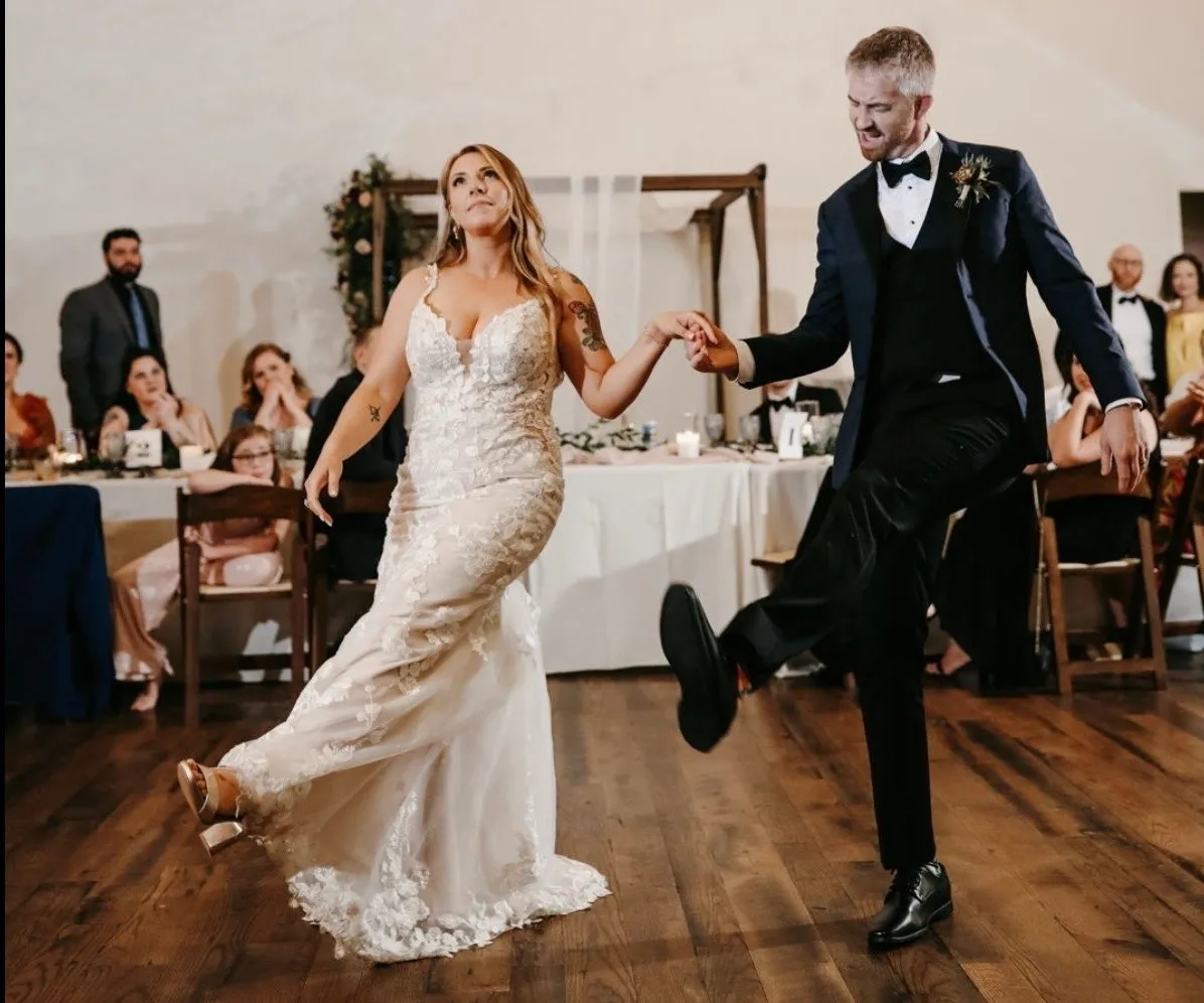A bride and groom mid-kick as wedding guests watch and laugh