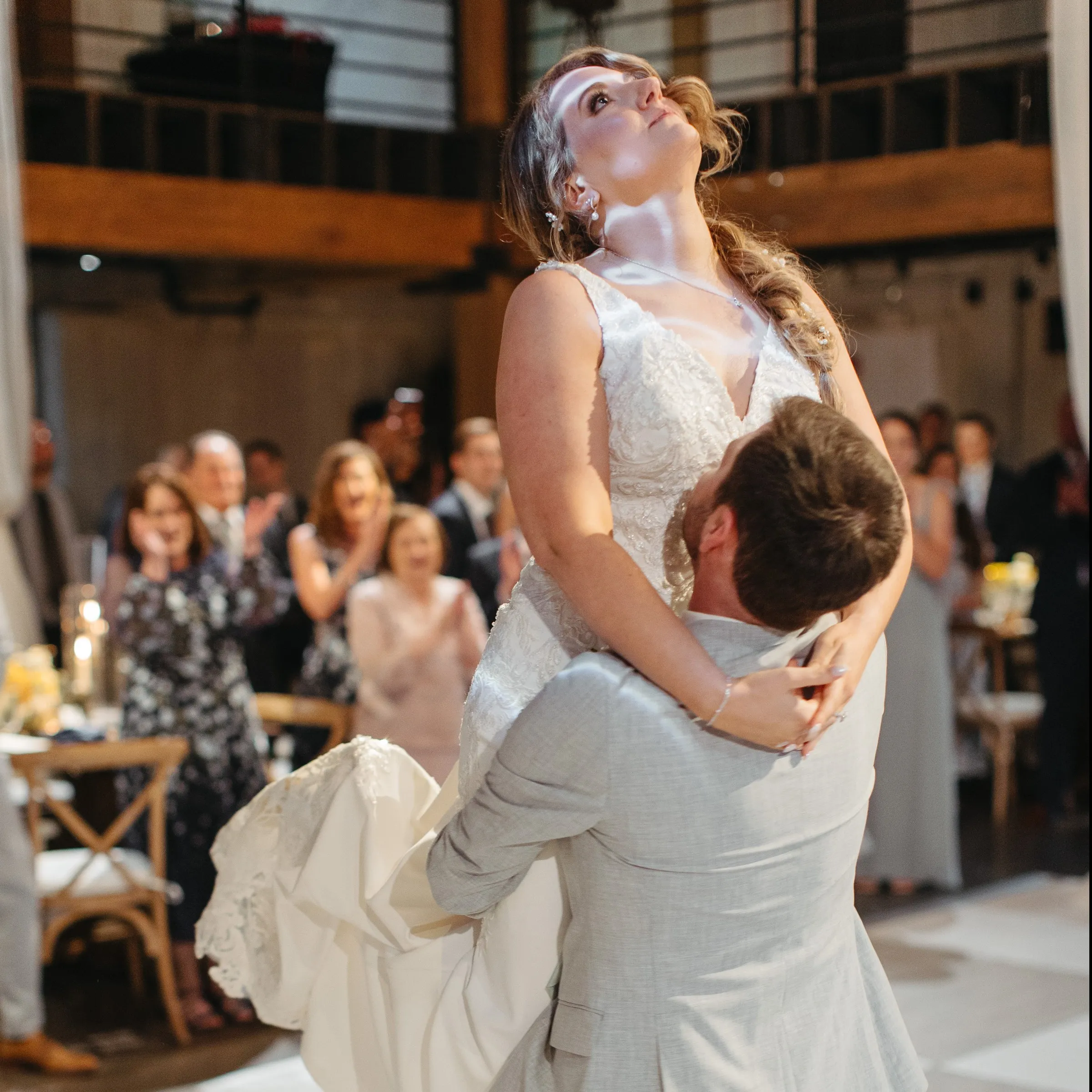 A groom lifts his bride during their first dance as guests cheer