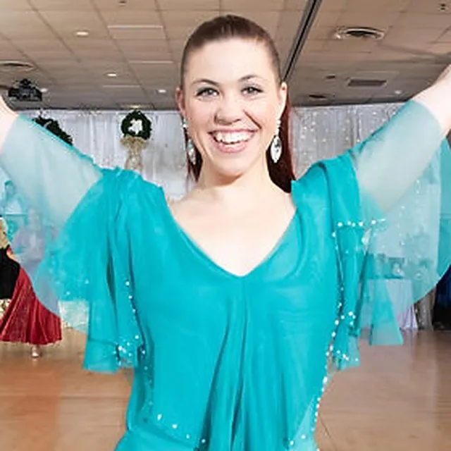 Rachel Miller smiling with arms raised on a ballroom floor
